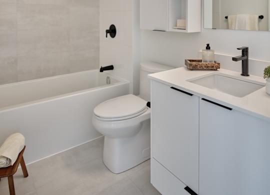 A white bathroom with a toilet, sink, and a chair.