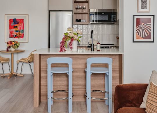 A kitchen with a bar stool and a refrigerator.