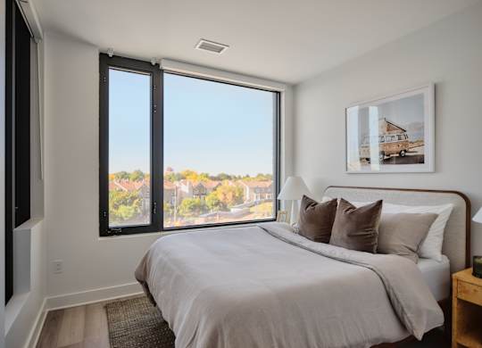 A bedroom with a large bed and a view of the city through the window.