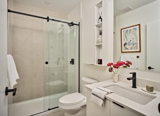 A white bathroom with a toilet, sink, and shower.