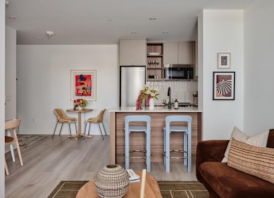 A kitchen with a bar stool and a table with a vase on it.