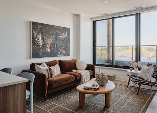 A living room with a brown couch, a coffee table, and a painting on the wall.