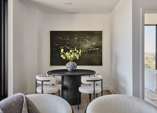 A painting of flowers is hanging on the wall above a table with chairs.
