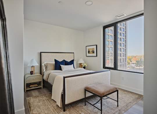 A bedroom with a large bed and a window overlooking a cityscape.