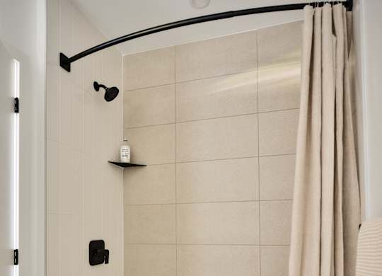 A white bathtub with a beige shower curtain.