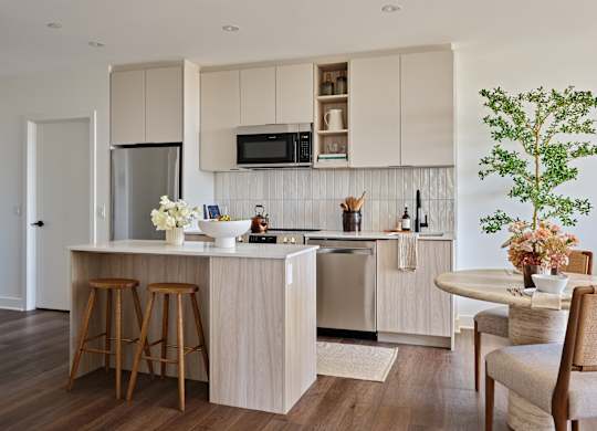 A kitchen with a white countertop and wooden bar stools.