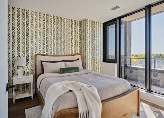 A bedroom with a large bed and a window overlooking a cityscape.