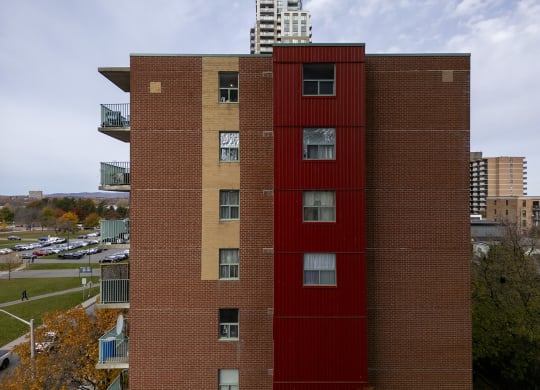 a tall building with a red facade and a city in the background