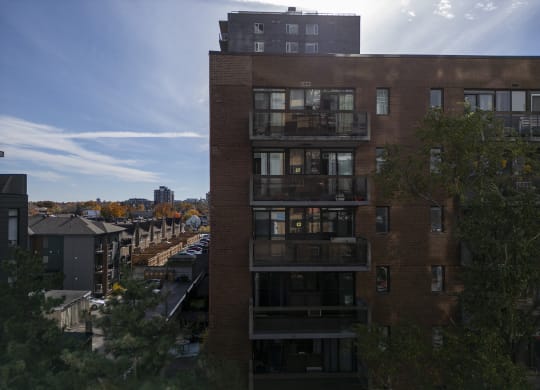 a tall brick building with balconies and a city in the background