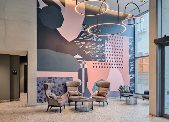 A modern lobby with a large mural and comfortable seating.