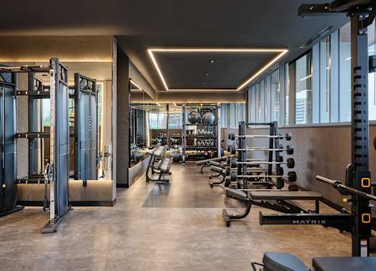 A gym with a variety of equipment including a squat rack, bench, and weights.