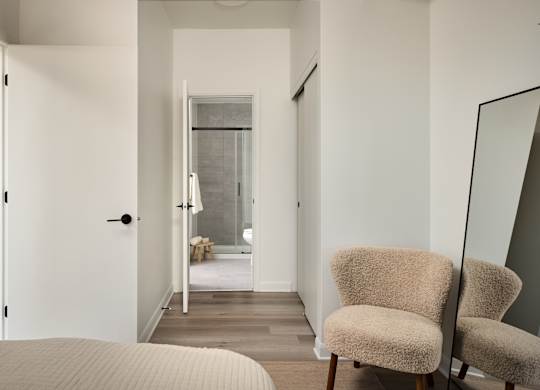 A bedroom with a bed, chair and mirror.