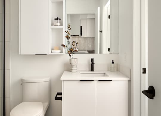A white bathroom with a toilet, sink, and medicine cabinet.