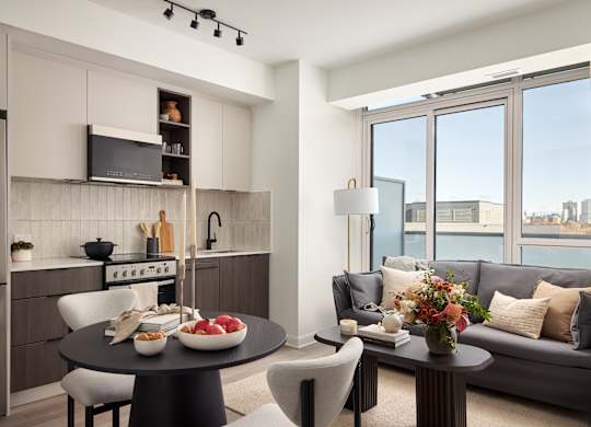 A modern kitchen with a dining table set with food and a couch with pillows.