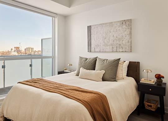 A bedroom with a large bed and a view of the city.