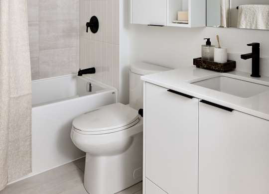 A white bathroom with a toilet, sink, and shower.