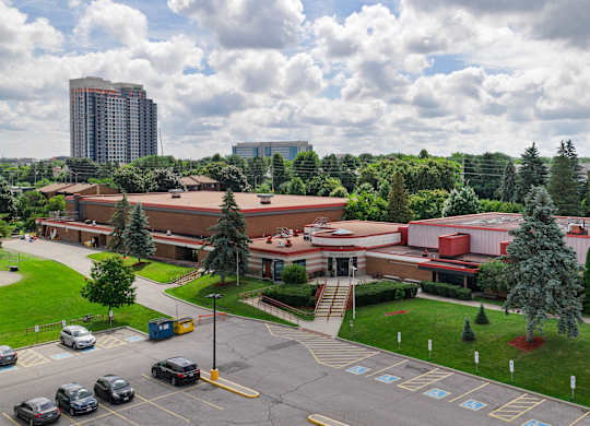 A parking lot in front of a building with a large red roof.