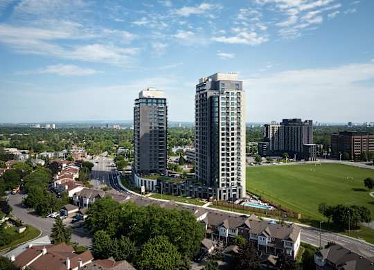 A cityscape with two tall buildings in the foreground and a park in the middle ground.