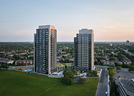 Two tall buildings are situated next to each other with a pool in the middle.
