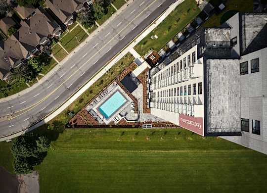 A swimming pool is surrounded by a grassy area and a building with a mural on the side.
