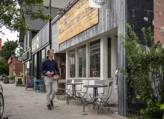 a man walks down a sidewalk in front of a restaurant