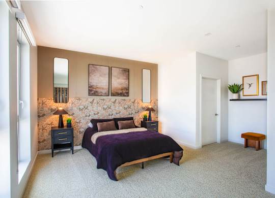A bedroom with a large bed and a nightstand with a lamp.
