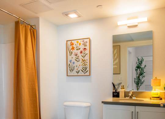 A bathroom with a toilet, sink, and a painting on the wall.