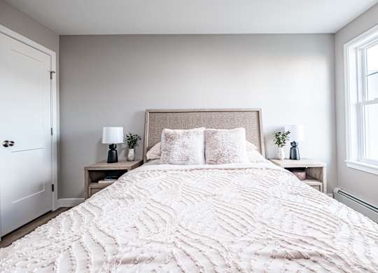 Bright bedroom with neutral tones and textured bedding at Windham Village Apartments, Maine, 04062