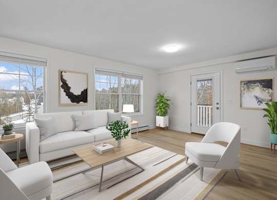 A living room with a white couch, a coffee table, and a large window with a view of the outdoors.