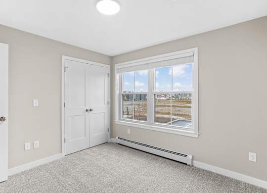 Spacious bedroom with plush carpeting, generous closet space, and natural light from a large window.