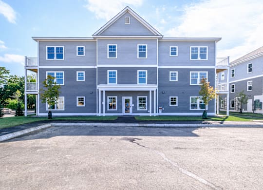 Three story residential building with gray siding at Windham Village Apartments, Maine, 04062