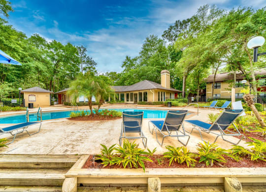 a swimming pool with chaise lounge chairs and trees in the background at Northlake Apartments, Jacksonville, 32218