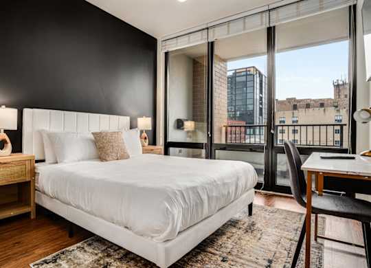 A bedroom with a large bed, a desk, and a chair.