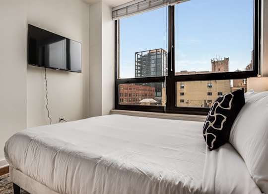 A bedroom with a large bed and a flat screen TV mounted on the wall.