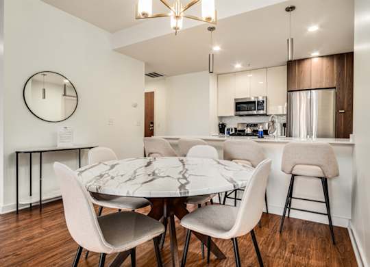 A modern dining room with a round mirror and a marble table.