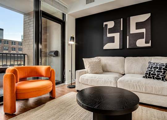A living room with a white couch and an orange chair.