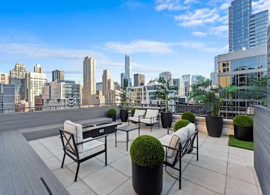A rooftop patio with chairs and tables overlooking a city skyline at Chateau on Wells, Chicago