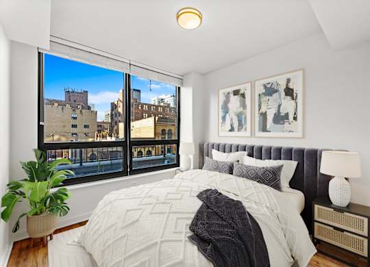 A bedroom with a large bed and a view of the city at Chateau on Wells, Chicago, IL