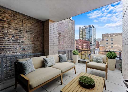 A balcony with a couch, chairs, and a table with a plant on it at Chateau on Wells, Chicago, 60654