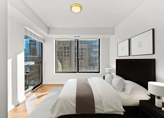 A bedroom with a large bed and a window overlooking a cityscape at Chateau on Wells, Chicago, 60654