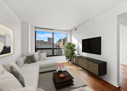 A modern living room with a large window and a flat screen TV. at Chateau on Wells, Chicago, Illinois