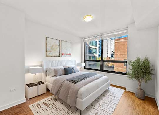 A bedroom with a large bed and a view of a cityscape through the window at Chateau on Wells, Chicago, IL