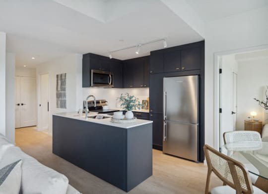 a kitchen with black cabinets and a stainless steel refrigerator