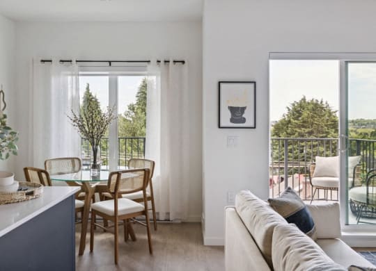 a living area with a couch and a table with chairs and a balcony