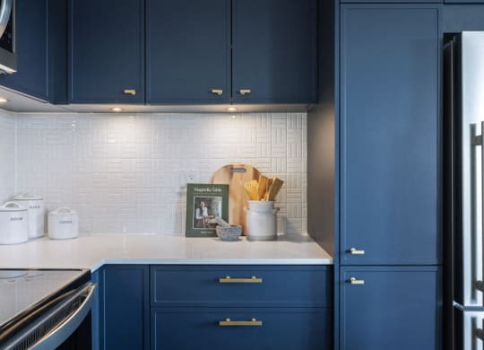 a kitchen with blue cabinets and a white counter top and a refrigerator