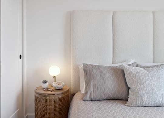 a bed with pillows and a nightstand with a lamp on it