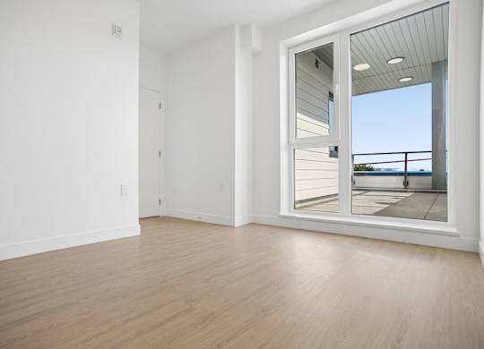A room with a sliding glass door leading to a balcony.