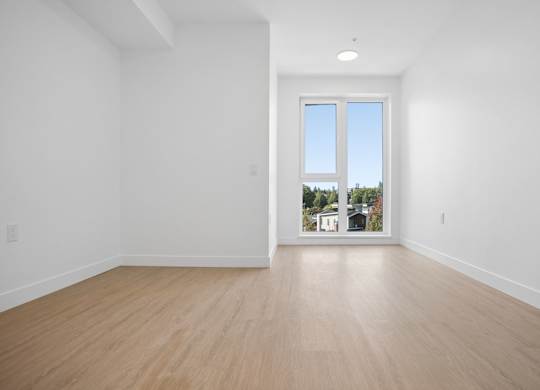 A room with a wooden floor and a window showing a view of a town.