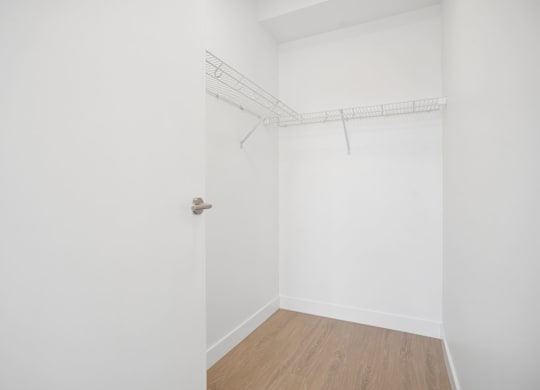 A white room with a door and a shelf.