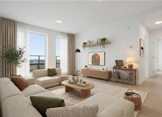 A living room with a white couch, a wooden coffee table, and a large window with curtains.